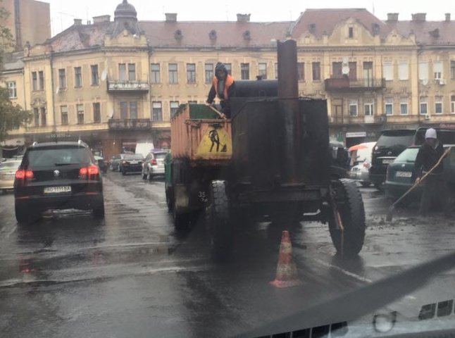 В Ужгороді комунальники під сильною зливою асфальтували дорогу